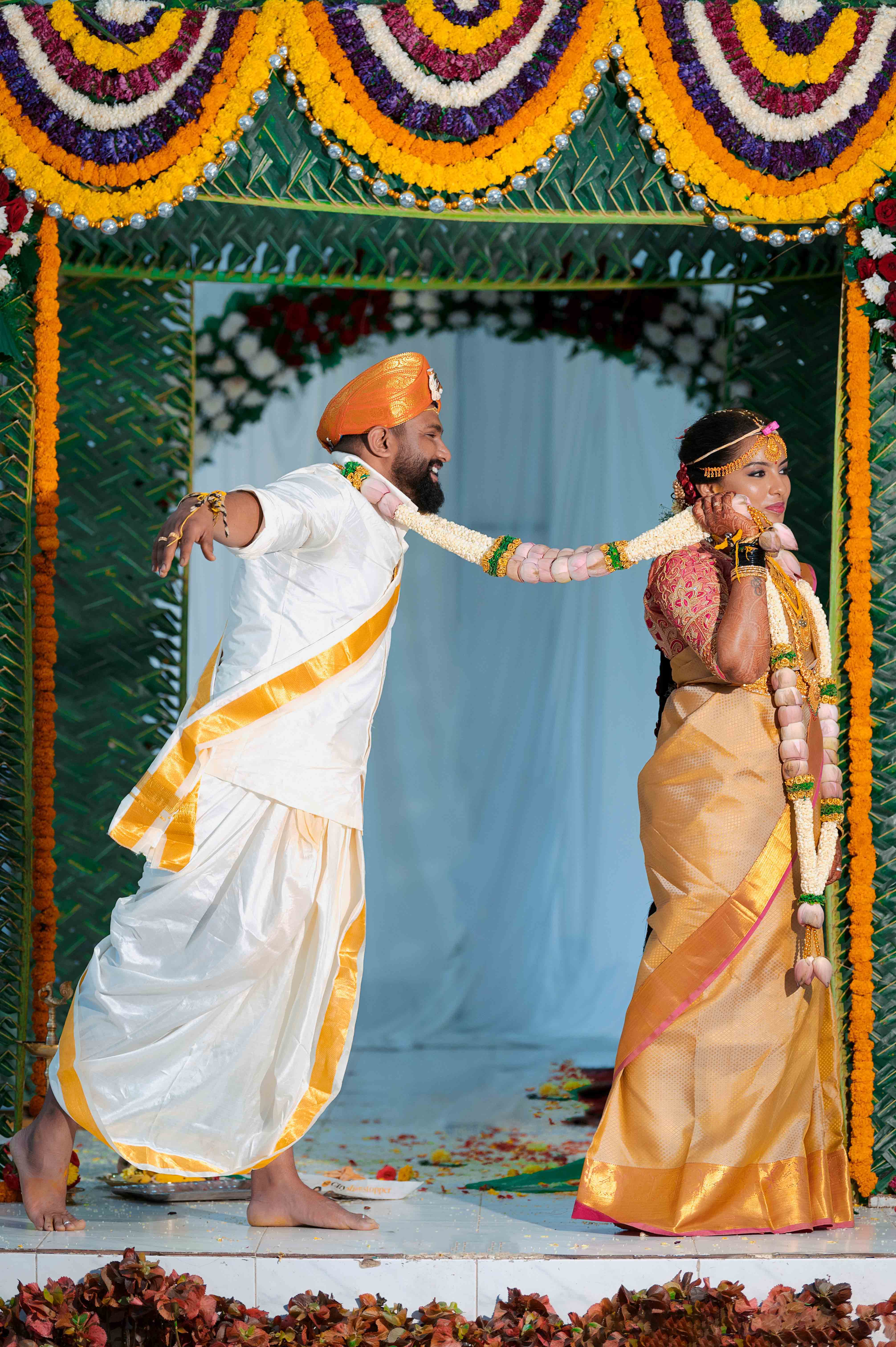 A couple holding wedding rings with intricate mehndi designs, vibrant attire, and a romantic vibe, perfect for wedding and love themes.